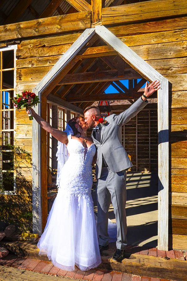 Wedding couple sharing a kiss in front of the chapel at Nelson Ghost Town