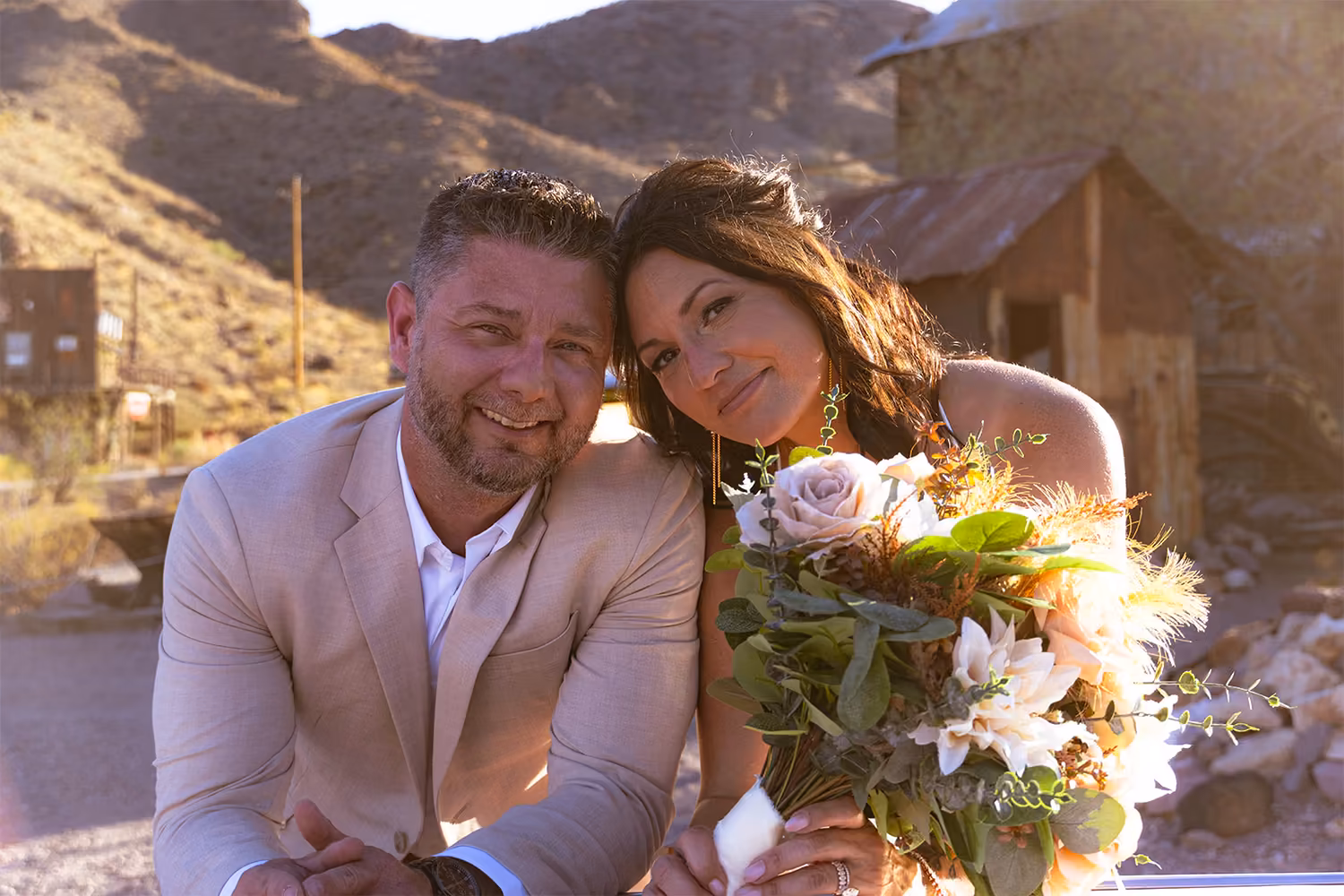 A newlywed couple at golden hour in Eldorado Canyon, the bride holding a desert-toned bouquet with Nelson Ghost Town's canyon hills behind them